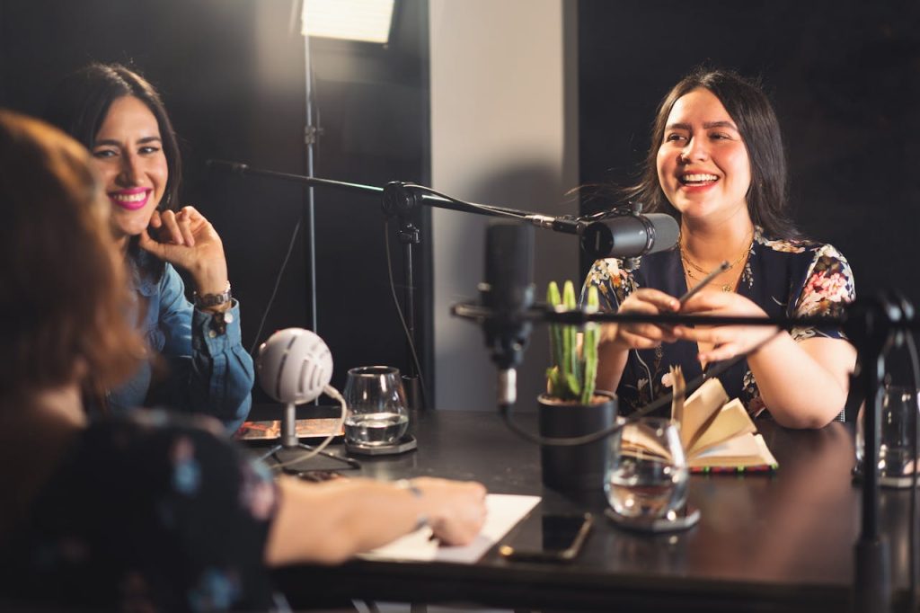 Three women enjoying a lively podcast recording session in a modern studio.